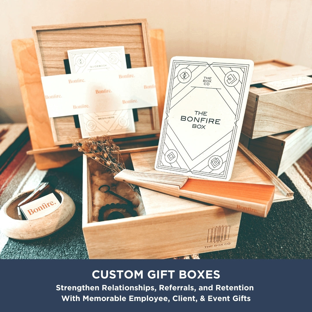 A set of wooden gift boxes from The Box Co, called The Housewarming Box, holds cards, dried flowers, and small gifts. Text below reads: “The Housewarming Box—make gift occasions meaningful and build lasting connections.”.