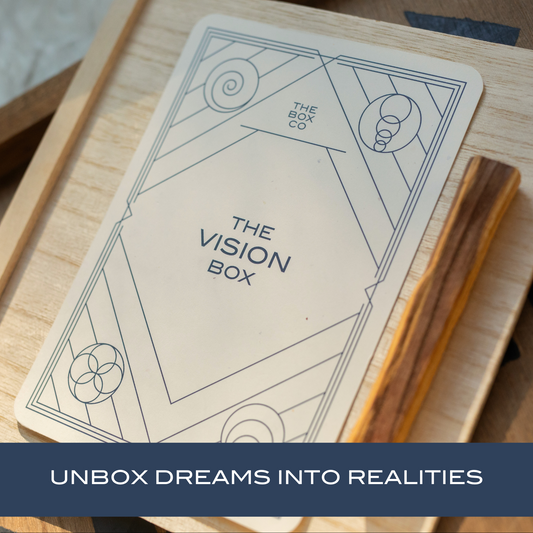 The Vision Box: card on a wooden box next to palo santo stick. Text overlay "UNBOX DREAMS INTO REALITIES".