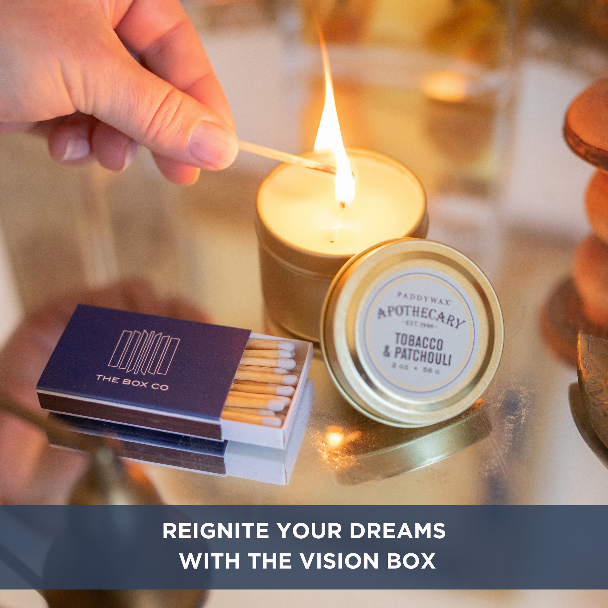 Close up of candle being lit, open matchbox with The Box Co logo and text overlay "REIGNITE YOUR DREAMS WITH THE VISION BOX".