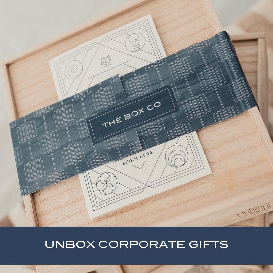 The Box for Business —a wooden box with blue wrapping. Text: “UNBOX CORPORATE GIFTS.” Ideal for work/professional related gifting