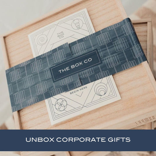 The Box for Business —a wooden box with blue wrapping. Text: “UNBOX CORPORATE GIFTS.” Ideal for work/professional related gifting