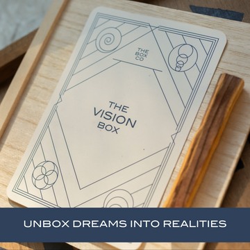 The Vision Box: card on a wooden box next to palo santo stick. Text overlay "UNBOX DREAMS INTO REALITIES".