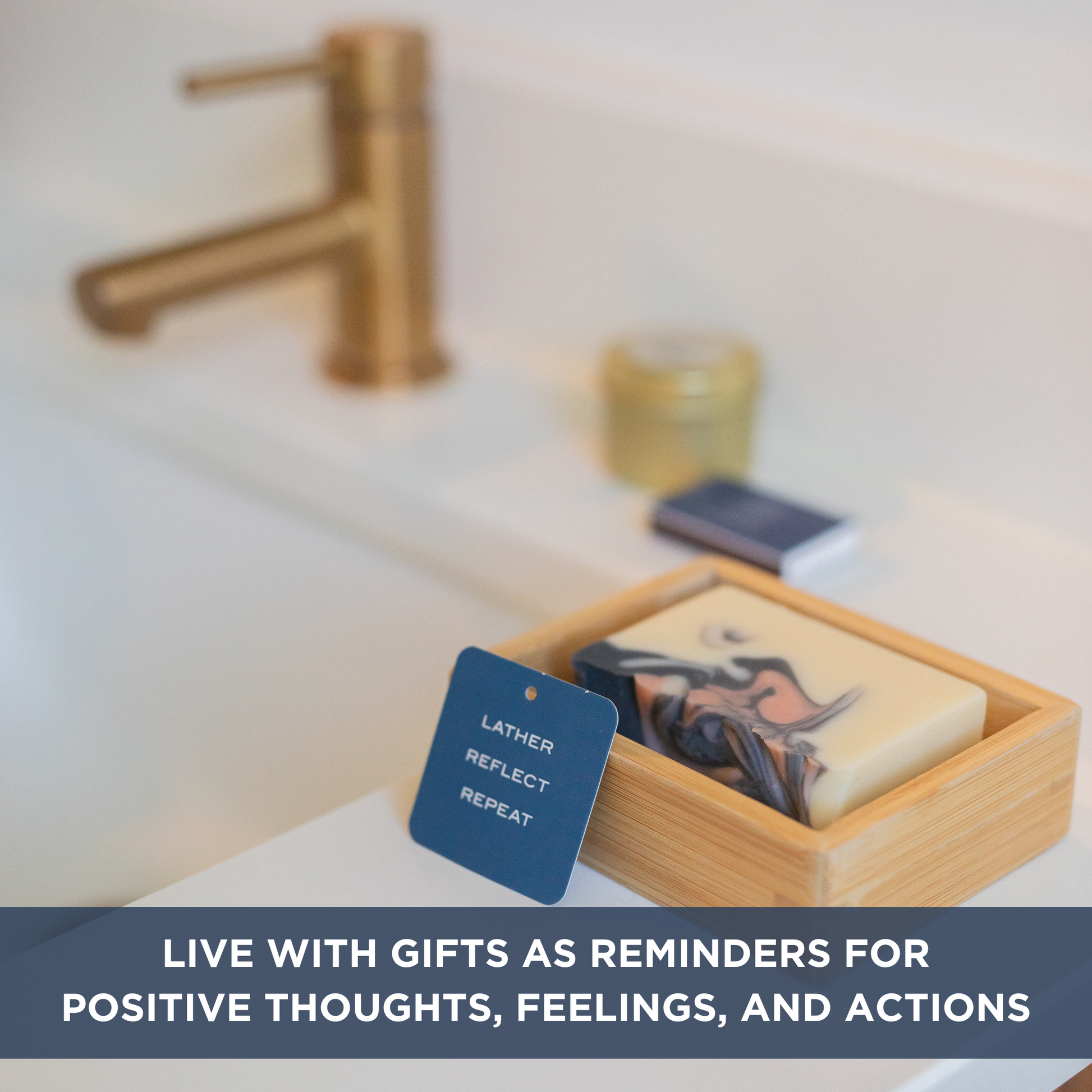 Bar of soap in a bamboo dish next to a card with the words "LATHER, REFLECT, REPEAT". Text overlay "LIVE WITH GIFTS AS REMINDERS FOR POSITIVE THOUGHTS, FEELINGS, AND ACTIONS".
