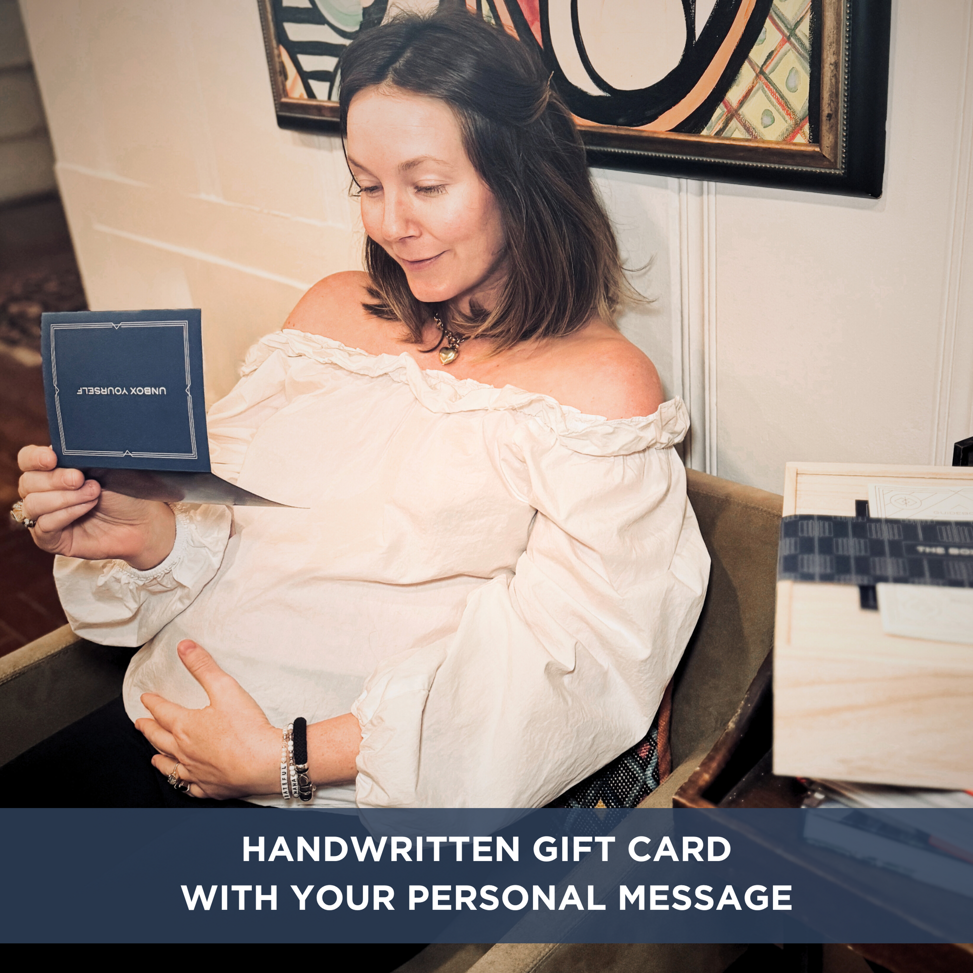 Pregnant woman smiling and holding her stomach while reading a card. Text overlay "HANDWRITTEN GIFT CARD WITH YOUR PERSONAL MESSAGE". 