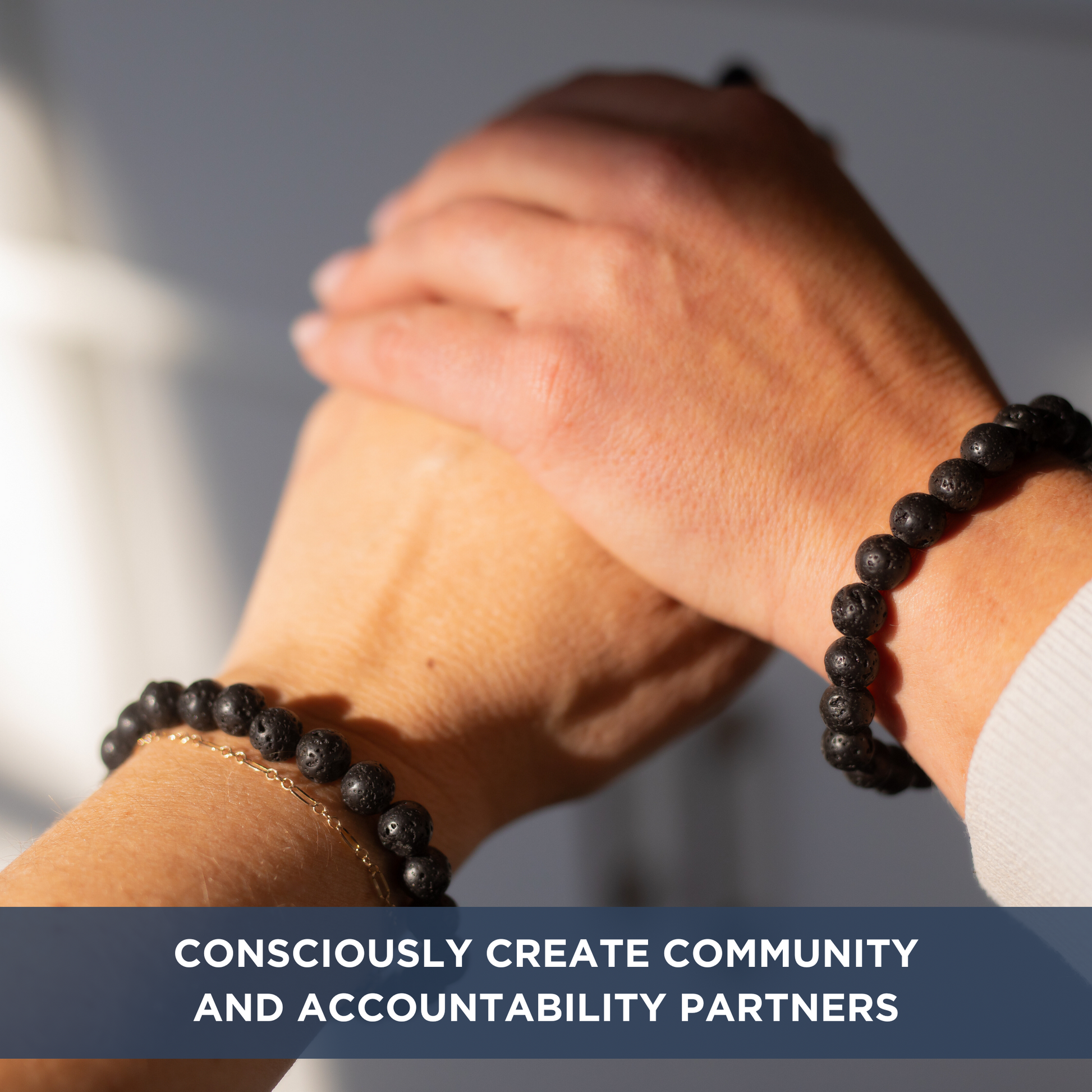 Two hands holding showing a close up of their beaded bracelets. Text overlay "CONSCIOUSLY CREATE COMMUNITY AND ACCOUNTABILITY PARTNERS".
