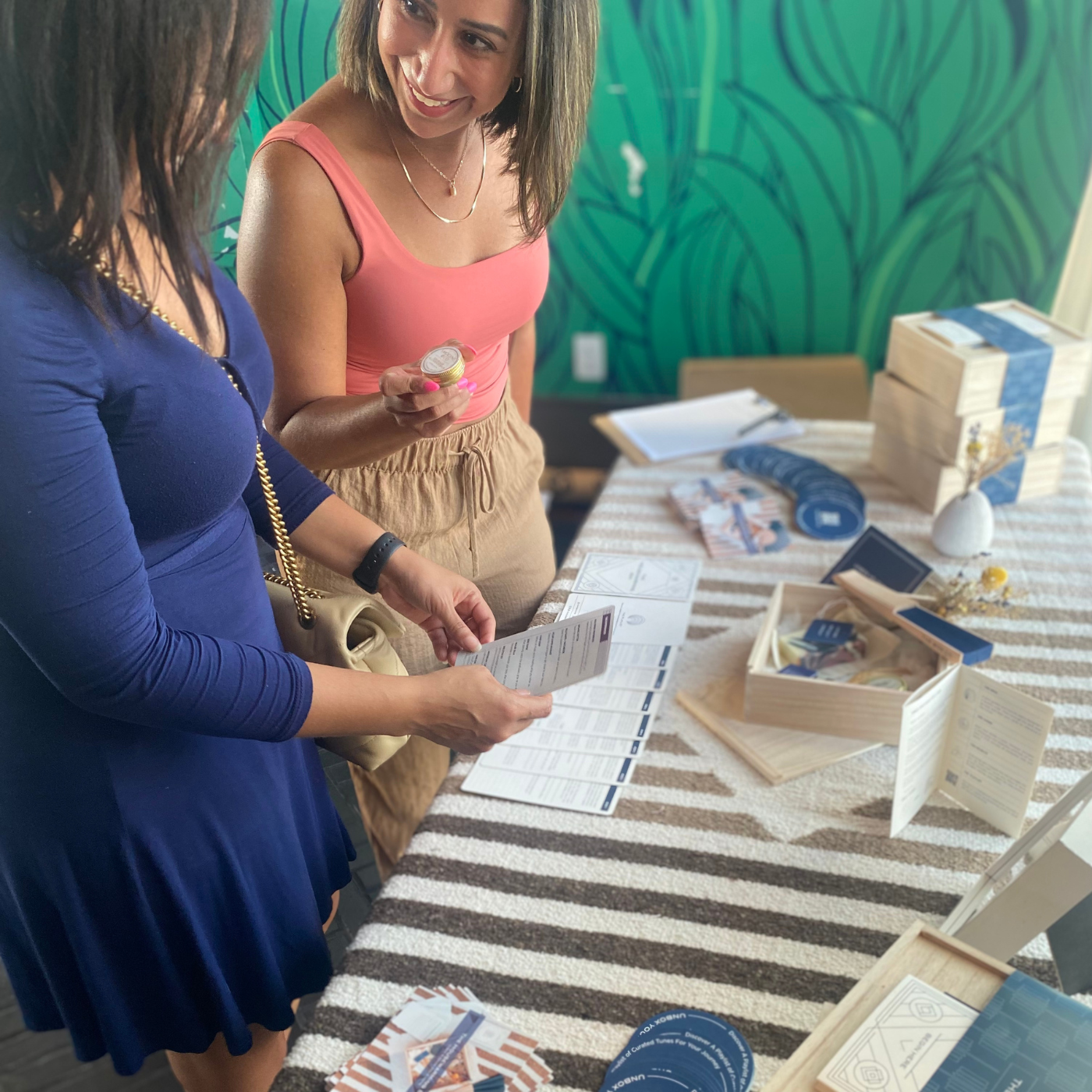 Two women smiling and standing at a table looking at The Box Co gift boxes. 